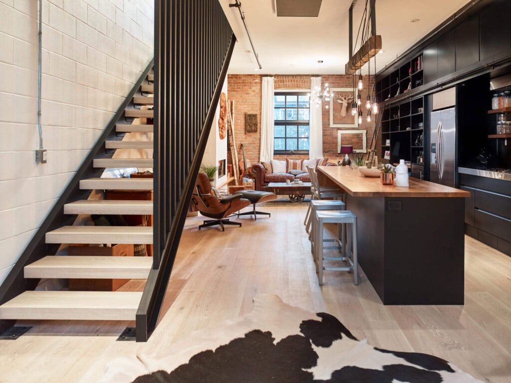 reVISION Sugar Coated Custom renovation Kitchen and Living- black cabinets and large island - brick walls