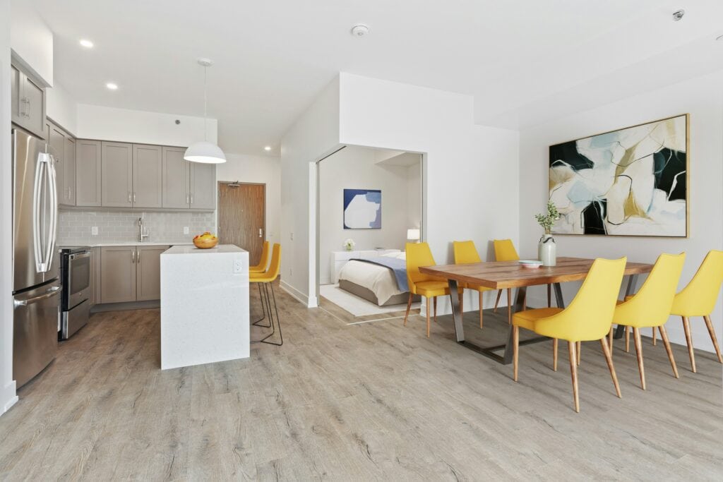 Bright and spacious Vancouver condo featuring an open-concept kitchen and dining space with contemporary furnishings and artwork, ideal for modern living.